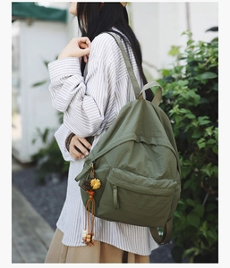 Detail of olive green backpack with ethnic style tassel and wooden bead charm