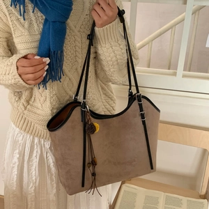 Detail of coffee brown suede tote bag featuring black leather trim and woven flower charm