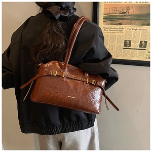 Close-up of brown glossy patent leather tote bag with vintage buckles and gold hardware
