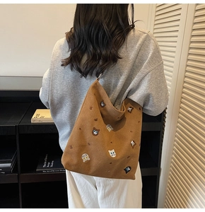 Detail of embroidered cat patterns on a brown canvas tote bag shown with model