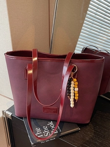 Sac fourre-tout vintage rouge foncé avec pendentif en perles sur un livre noir