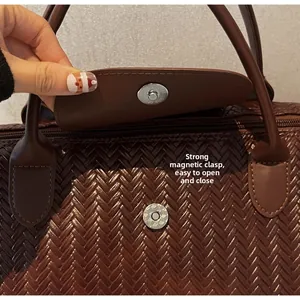 Détail du sac de voyage marron tressé montrant le fermoir magnétique et la texture