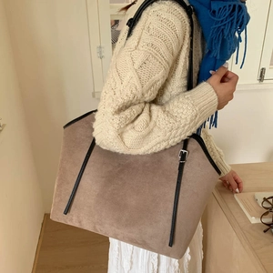 Detailed view of large brown suede tote bag with black leather straps on a female model