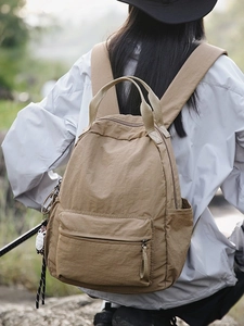 Minimalist khaki nylon backpack for students shown in an outdoor lifestyle setting