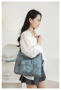 Close-up of blue washed canvas tote with wide strap on model in minimalist home setting