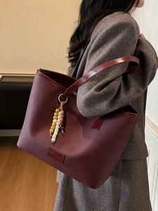 Grand sac cabas bordeaux rétro avec pompon perlé sur une bandoulière d'épaule