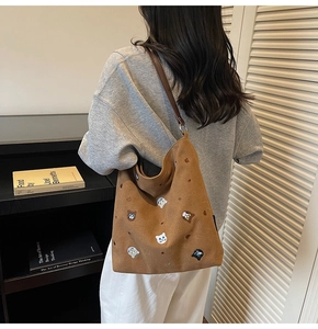 Detail of dark brown canvas tote bag featuring embroidered cat motifs and leather strap