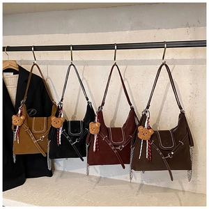 Detailed close-up of retro suede crossbody bags with cute bear charms in four classic colors