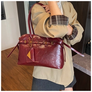 Detail of burgundy patent leather tote bag with glossy finish and gold metal chain hardware