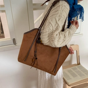 Detail of vintage brown suede tote bag with leather handles and decorative beaded tassels