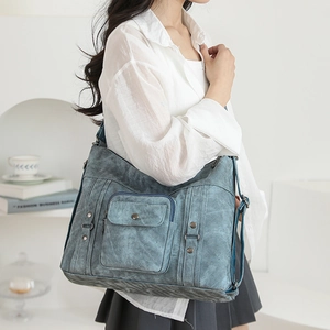 Detailed macro view of retro rivet buckles and front pocket on washed blue canvas tote bag