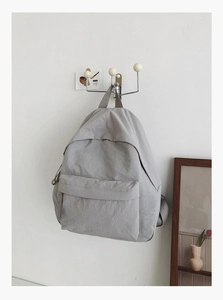 Detail of a lightweight minimalist grey nylon backpack with large front zip pocket