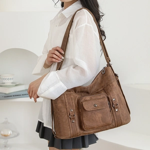 Close-up of vintage brown leather shoulder bag featuring metal buckles and textured finish