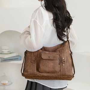 Detailed close-up of a vintage dark brown tote bag with matte faux leather and metal buckles