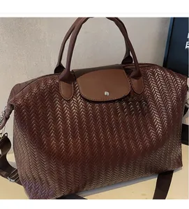Détail d'un sac de voyage tissé marron avec rabat en cuir et bouton pression en métal