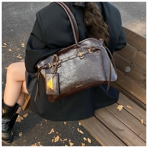 Detail of dark brown tote bag with oily leather texture and gold chain coin purse