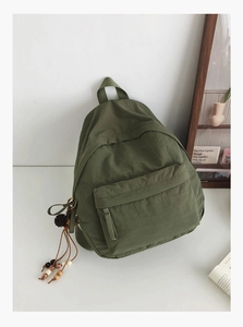 Detail of army green nylon backpack featuring bohemian beaded tassel and front pocket