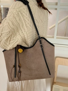 Vintage brown faux suede tote bag with flower charm and black straps on a white knit sweater