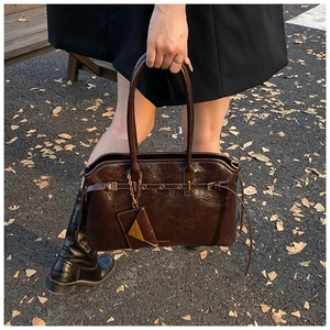 Detail of dark brown oil wax leather tote bag with vintage texture and brand embossing