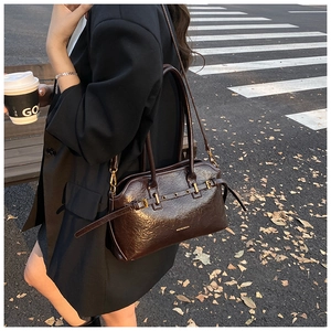 Detail of dark brown glossy leather tote bag with metal buckles on urban street background