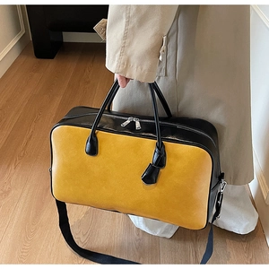 Détail du sac de voyage bicolore jaune et noir avec doubles poignées et zips métalliques