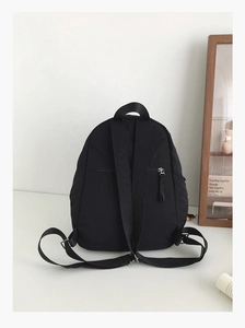 Detailed back view of a black nylon backpack showing adjustable straps and anti-theft pocket