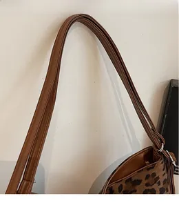 Close-up of smooth synthetic leather straps and silver buckle on a leopard print tote