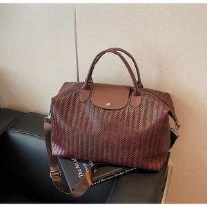 Détail du sac de voyage marron avec poignées en cuir et motif tissé à points de croix