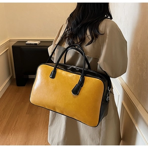 Détail d'un grand sac cabas contrasté jaune et noir porté par un mannequin dans une pièce