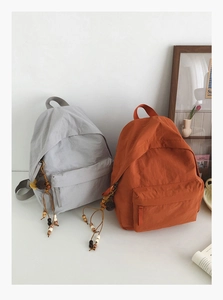 Detailed view of lightweight nylon backpacks with fringe tassels in a minimalist setting