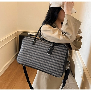 Gros plan d'un grand sac cabas rayé avec poignées en similicuir et large bandoulière réglable