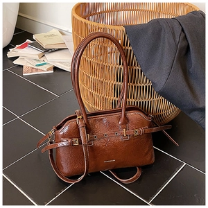 Detailed view of caramel brown tote bag featuring glossy crinkled leather and buckle detail
