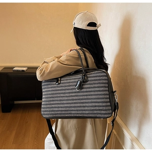 Détail d'un grand sac cabas rayé avec finitions en cuir porté par un mannequin