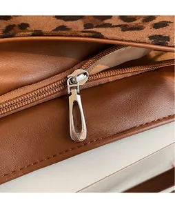 Detail of silver oval zipper pull on brown lychee leather and leopard print fabric