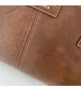 Detailed close-up of brown faux leather texture with double stitching and embossed logo