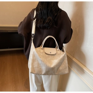 Détail du sac de voyage tissé crème avec poignées en cuir et bandoulière réglable