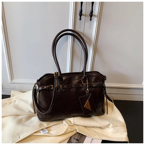Close-up of deep coffee oil wax leather tote with adjustable gold buckle and brand logo