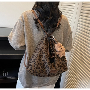 Detail of hobo bag with leopard print canvas texture and brown bear charm on strap