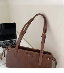 Detail view of brown leather tote bag with adjustable gold buckles and side drawstrings