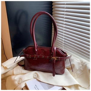 Detail view of burgundy tote bag in wrinkled patent leather with stylish buckle straps