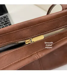 Macro detail of smooth golden zipper and lychee pattern leather on brown shoulder bag
