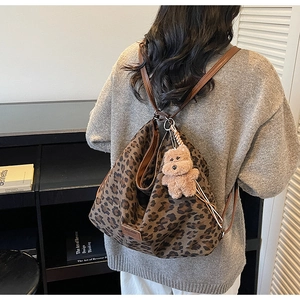 Detail of leopard print backpack with brown straps and cute plush bear accessory