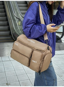 Model wearing a khaki multi-pocket travel bag on an escalator showing its large size