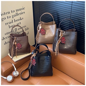 Detail view of four crocodile pattern bucket bags with bear charms on a leather sofa