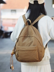 Minimalist brown nylon backpack for women featuring colorful decorative pendant details