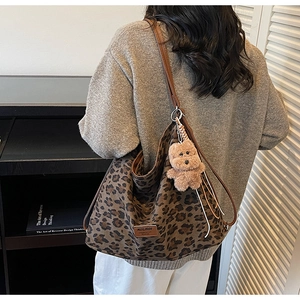 Leopard print tote bag detail featuring premium leather straps and a plush bear charm