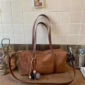 Primer plano de bolso almohada vintage marrón esmerilado con colgante de felpa y cremallera