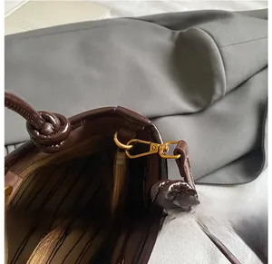 Détail du sac en cuir marron montrant le crochet doré et la doublure en tissu rayé
