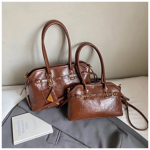 Detail of vintage brown crinkled leather tote bag set with golden hardware and straps