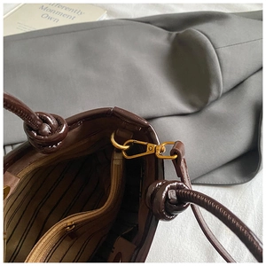 Détails du sac seau en cuir marron foncé avec doublure rayée et finitions dorées